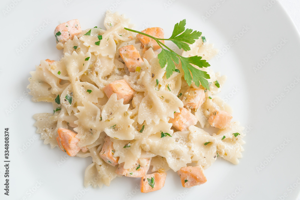 salmon chops and farfalle pasta with cream sauce decorated with parsley salmon chops and farfalle pasta with cream sauce decorated with parsley