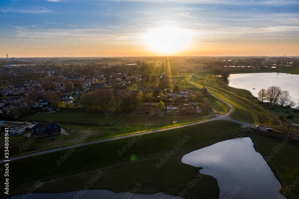 Village next to dike at sunset in the Netherlands, netherlands, Gelderland, Beuningen, Weurt. Aerial made with drone at the floodplain.