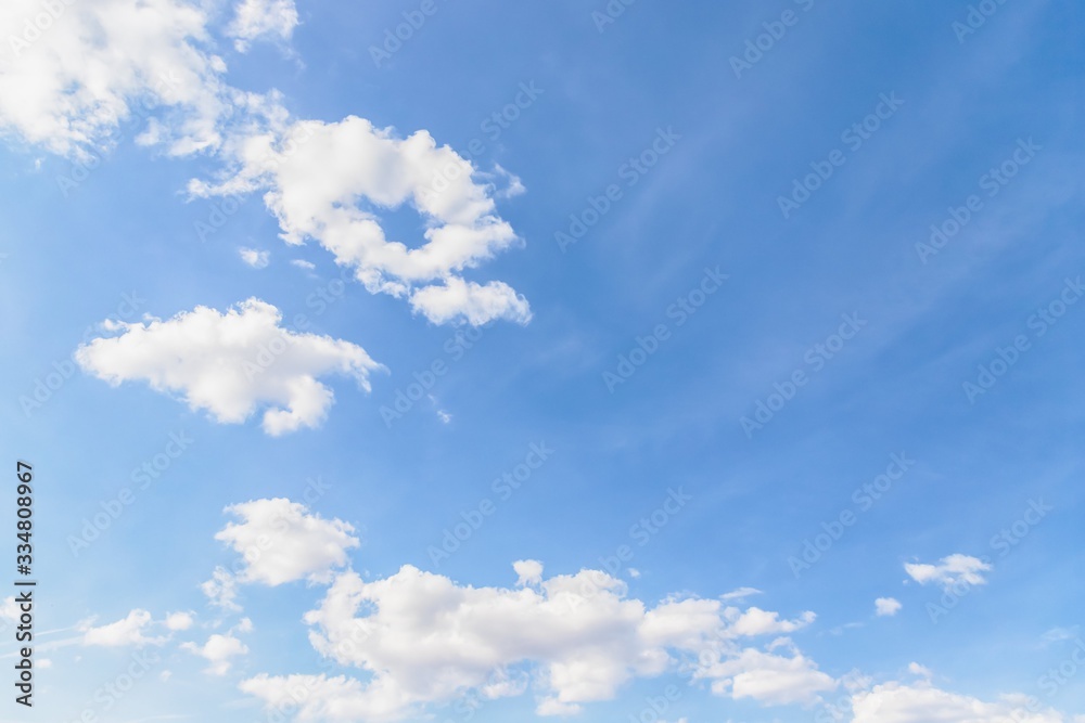 Fototapeta premium Beautiful white few soft fluffy clouds on a blue sky background. Copy space