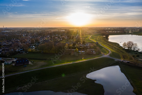 Village next to dike at sunset in the Netherlands, netherlands, Gelderland, Beuningen, Weurt. Aerial made with drone at the floodplain. © Rob