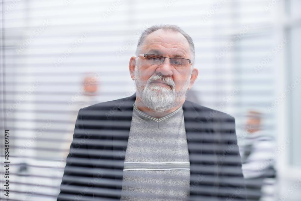 elderly successful businessman looking through office window. elderly successful businessman looking through office window.