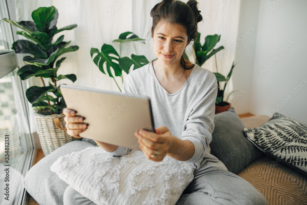 Hipster girl using tablet, working or chatting from home during quarantine in modern room . Stay home stay safe. Isolation at home to prevent virus epidemic. Home office Hipster girl using tablet, working or chatting from home during quarantine in modern room . Stay home stay safe. Isolation at home to prevent virus epidemic. Home office