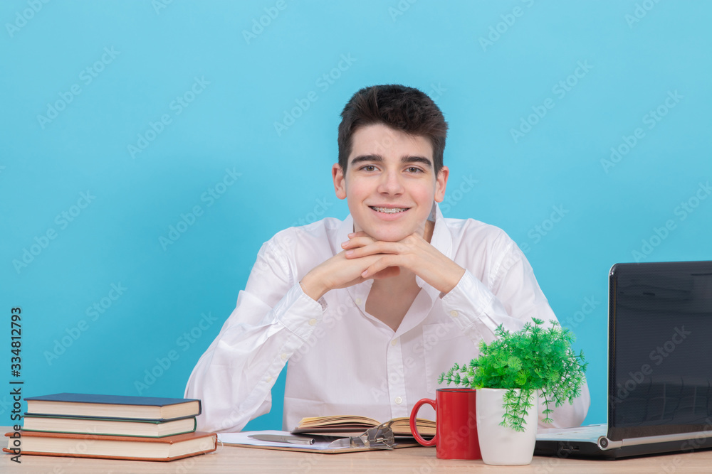 teenage student at the desk with computer and colored background