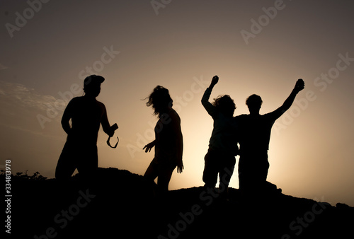 silhouettes of young people dancing on sunset
