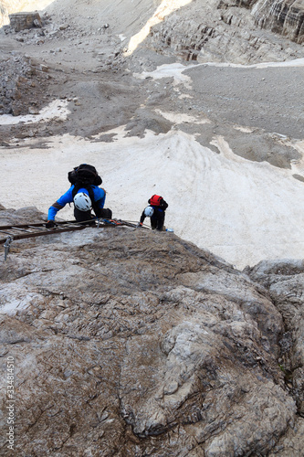 People climbing a ladder on Via Ferrata Sentiero Brentari in Brenta Dolomites mountains, Italy photo