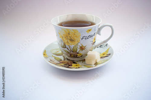 Cup with tea and sugar cubes on a white background