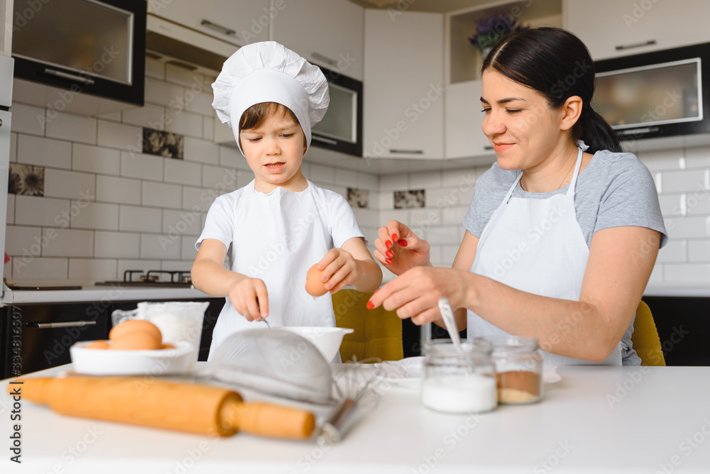 Young mother and her little son baking cookies together at home kitchen Young mother and her little son baking cookies together at home kitchen