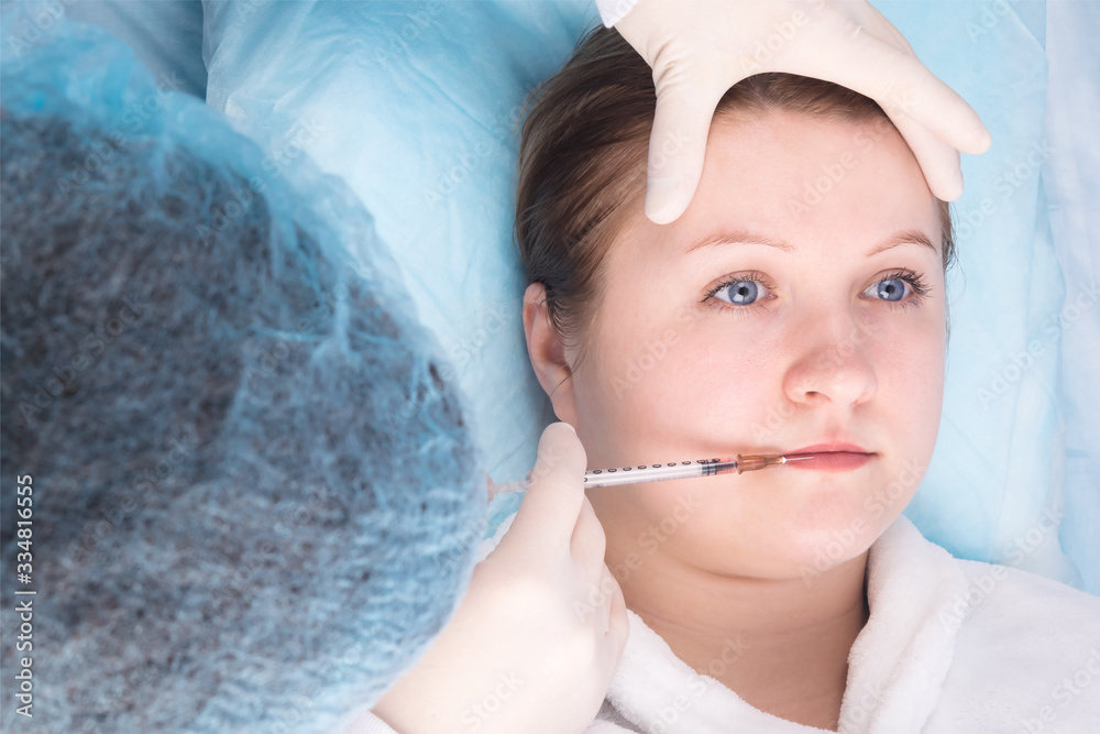 doctor makes an injection to increase the lips of a girl, top view