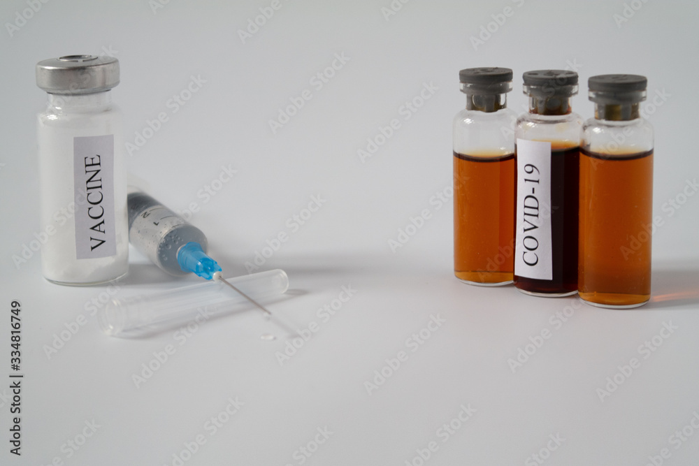 A medical syringe and test tubes with a liquid labeled COVID-19 and a white powder labeled vaccine. Flasks with a virus test and an antiviral drug. Concept of vaccination and medicine for a disease.