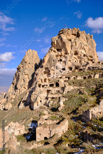 Uchisar Castle in Cappadocia, on a biright winter day, with blue sky and puffy clouds photo