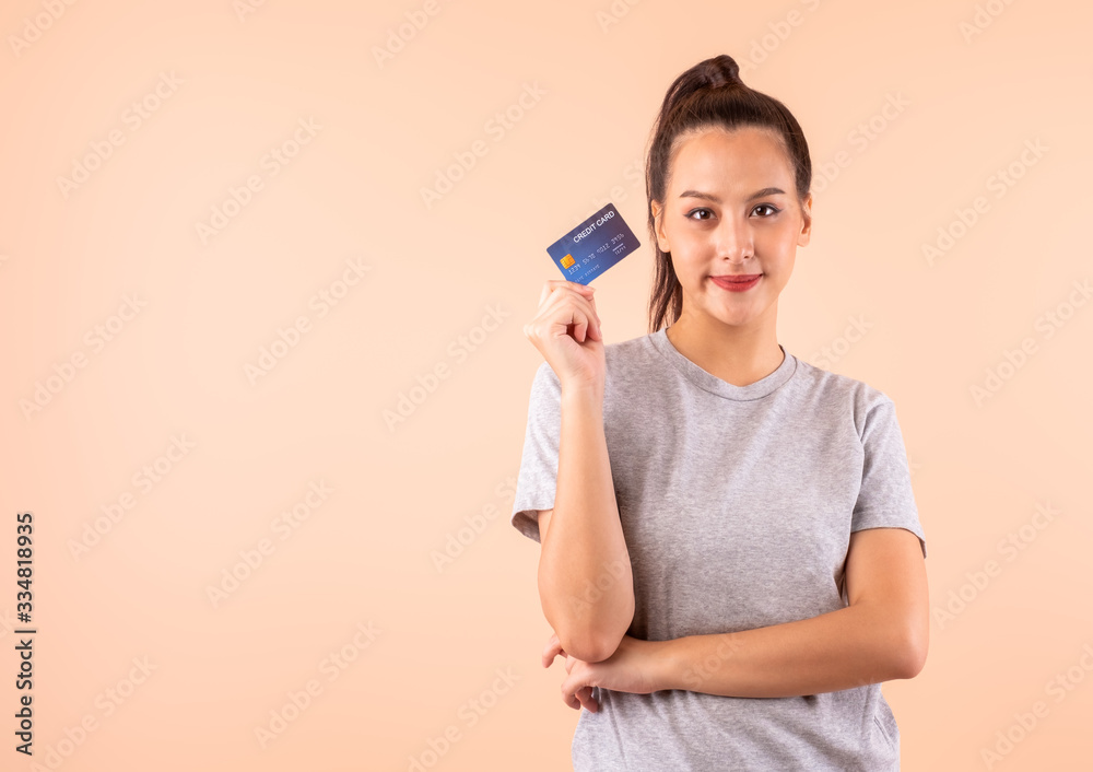 Young Asian woman holding credit card over pink background with copy space, credit card payment for cashless online shopping concept Young Asian woman holding credit card over pink background with copy space, credit card payment for cashless online shopping concept