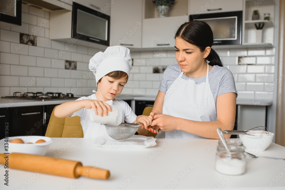 Young mother and her little son baking cookies together at home kitchen Young mother and her little son baking cookies together at home kitchen