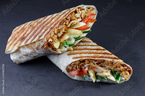 Shawarma with vegetables and meat on a wooden stand.