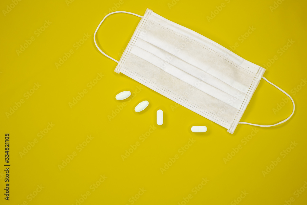 corona virus mask for protecting against the ncov covid-19 virus with white pills on yellow background corona virus mask for protecting against the ncov covid-19 virus with white pills on yellow background