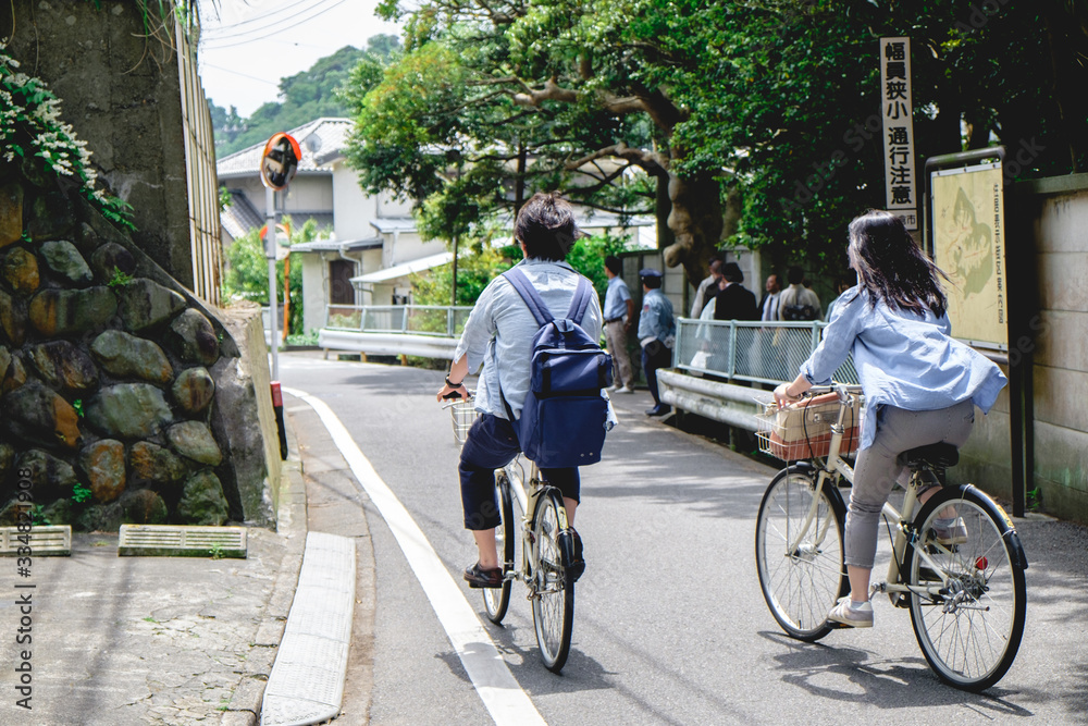 Couple in bikes from back at streets of Kamakura, Japan