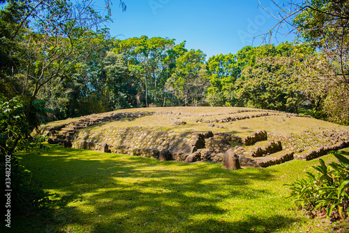 mayan ruin of takalik abaj, ancient temple and steps built with stones, with huge forest and plants around photo