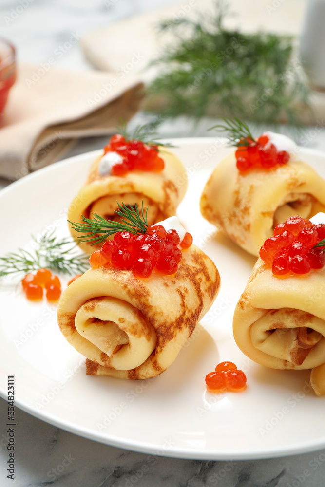 Delicious thin pancakes with red caviar on white marble table, closeup Delicious thin pancakes with red caviar on white marble table, closeup