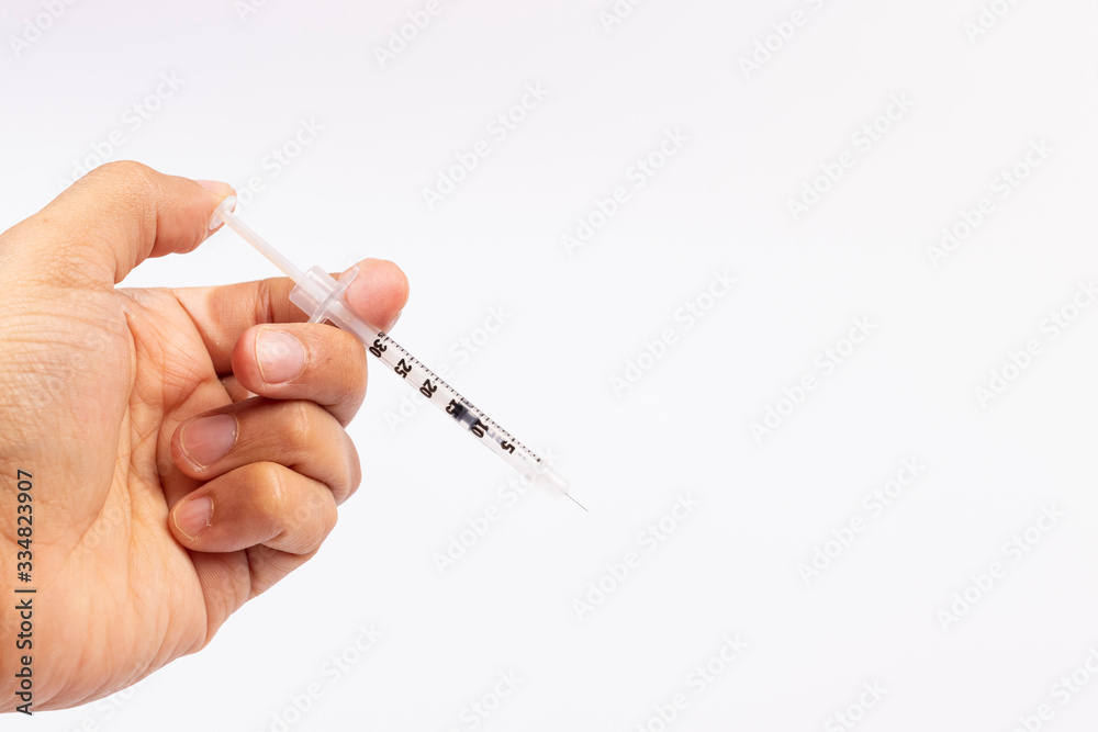 Hand holding an insulin syringe before being used Hand holding an insulin syringe before being used