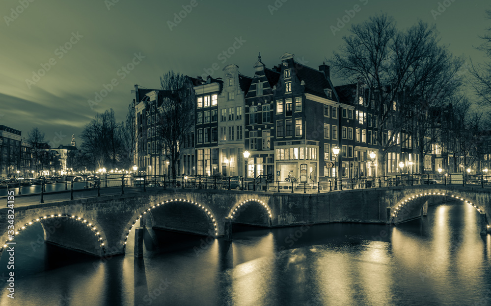 Amsterdam, the Netherland - March, 28th 2020 : Night scape of famous Amsterdam bridge with illuminated arcs long exposure shot at night with muted colors 
