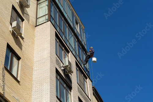 Industrial climbing. Climber wash windows in a high-rise building. Cleaning of windows glass elements.