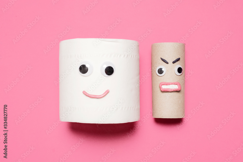 Smiling happy full toilet paper roll next to an angry empty toilet paper roll on a pink background with copy space and room for text. Smiling happy full toilet paper roll next to an angry empty toilet paper roll on a pink background with copy space and room for text.