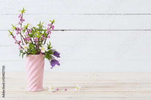 spring flowers in vase on white wooden background © Siarhei