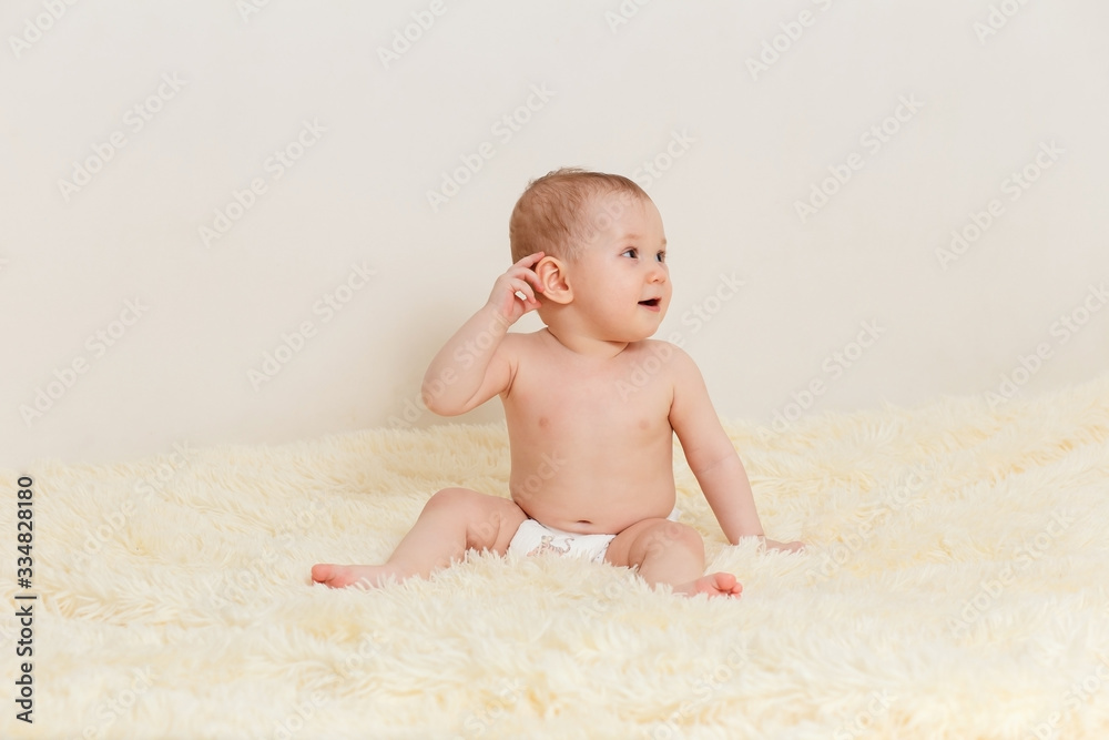cute baby girl in a diaper sits well on a fluffy blanket on a white background cute baby girl in a diaper sits well on a fluffy blanket on a white background