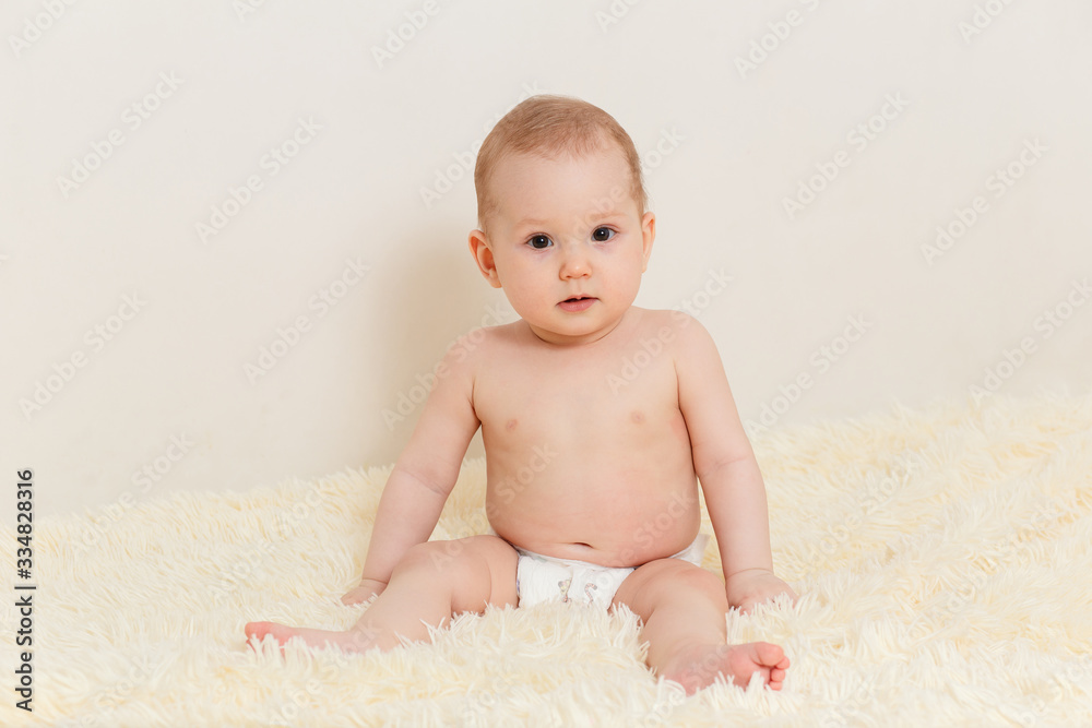 cute Caucasian baby girl in a diaper sits well on a fluffy blanket on a white background cute Caucasian baby girl in a diaper sits well on a fluffy blanket on a white background