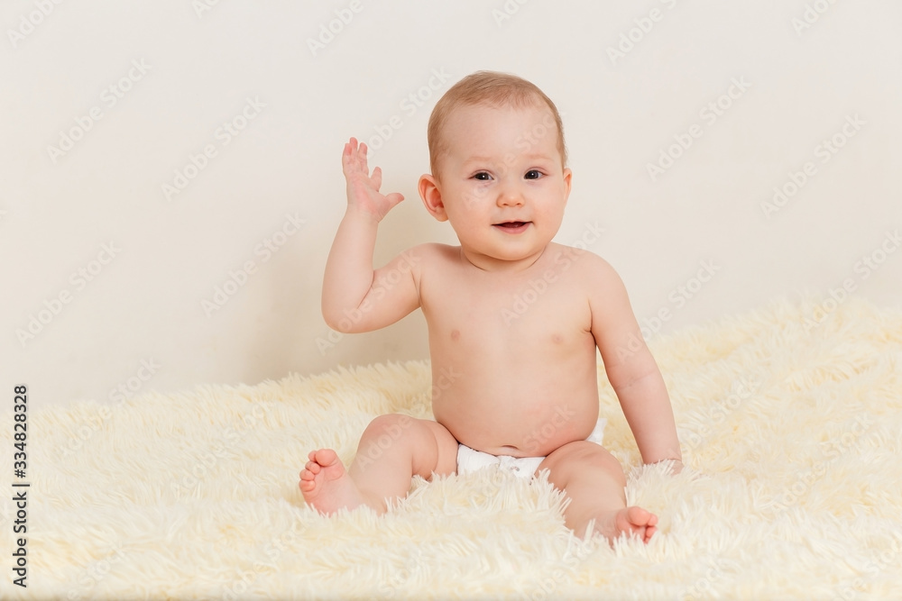 Caucasian baby girl in a diaper sits well on a fluffy blanket on a white background and looks at the camera Caucasian baby girl in a diaper sits well on a fluffy blanket on a white background and looks at the camera