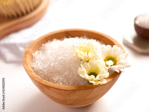 Spa composition. Sea salt, bath towel and flowers on white background. Close up. Home care concept