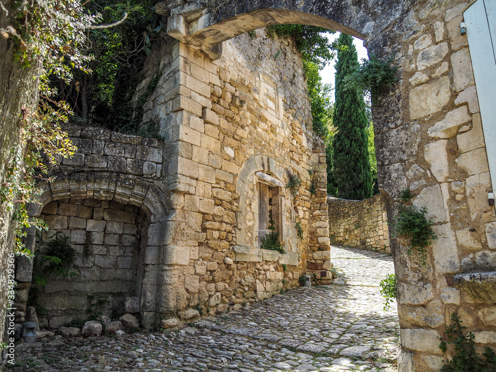 Medieval windows arches and doors in Provence, surrounded by greenery.