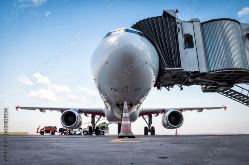 A white passenger aircraft at the jet bridge and is loaded with baggage photo