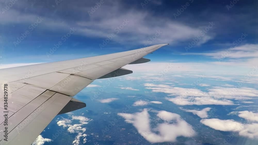 accelerated flight above the clouds, view from the eluminator on the wing of an airplane and flying clouds above the ground, time lapse