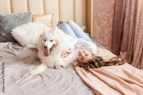 Home portrait of cute child hugging with dog on the sofa