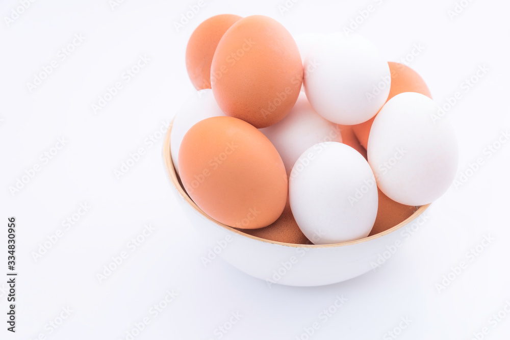 Brown and white eggs in wooden bowl on white background Brown and white eggs in wooden bowl on white background