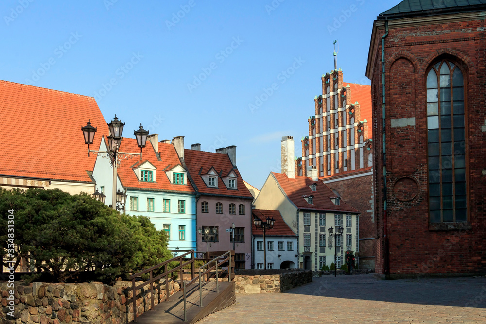 Old town square with beautiful St. John's Church and cute red roofed houses in Riga, Latvia Old town square with beautiful St. John's Church and cute red roofed houses in Riga, Latvia