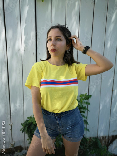 beautiful woman in yellow shirt and denim shorts in front of wooden background