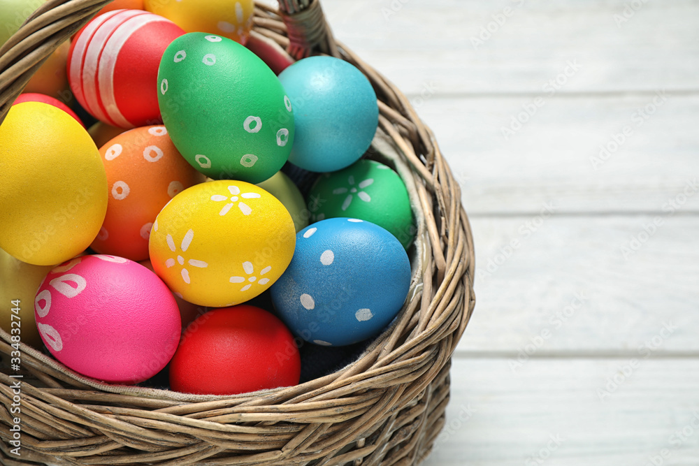 Colorful Easter eggs in basket on white wooden table, closeup Colorful Easter eggs in basket on white wooden table, closeup