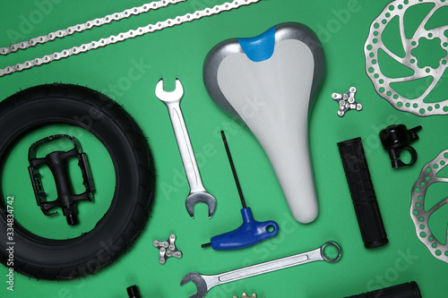 Set of different bicycle tools and parts on green background, flat lay