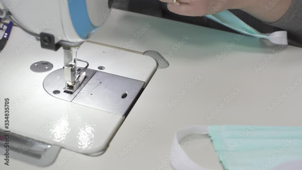 Experienced seamstress sews a protective mask from fabric on an urgent order during an epidemic. Experienced seamstress sews a protective mask from fabric on an urgent order during an epidemic.