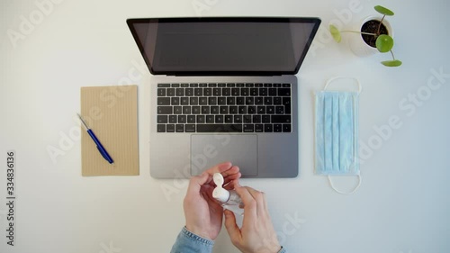 Modern workspace, a male uses hand sanitizer to disinfect his hands at workplace