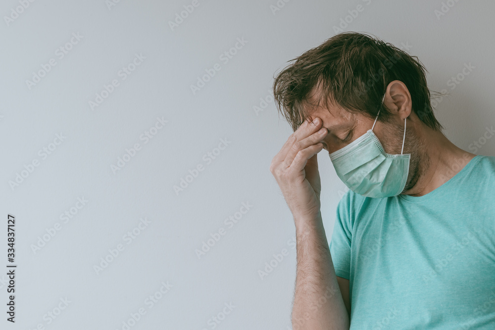 Man with mask having migraine headache as Covid-19 symptoms Man with mask having migraine headache as Covid-19 symptoms