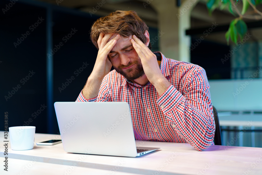 Tired businessman working on his computer in open space office. End of the working day Tired businessman working on his computer in open space office. End of the working day