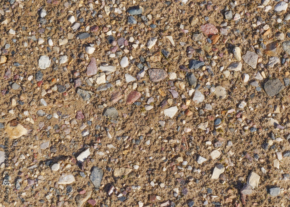 Close-up view of the wet fine sand with many small multicolored stones. Natural texture or background, copy space Close-up view of the wet fine sand with many small multicolored stones. Natural texture or background, copy space