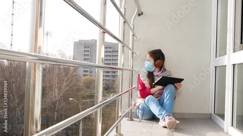 Wallpaper Mural teenager girl in mask and headphones, typing, working on tablet, on open balcony. spring sunny day. distance learning during quarantine. stay, study at home. coronavirus epidemic. Torontodigital.ca
