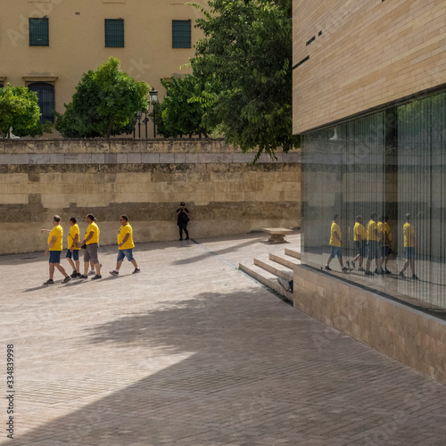 Grupo de hombres con camisetas amarillas reflejados en un cristal en la ciudad de Córdoba photo