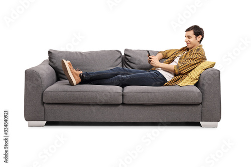 Relaxed young man lying on a sofa with a mobile phone