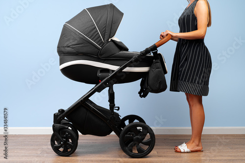 Woman with the baby carriage in the room. Close up.