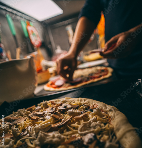 Closeup hand of chef baker in white uniform making pizza at kitchen