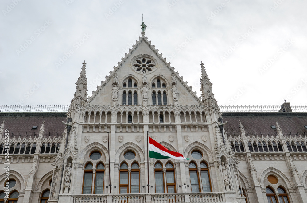 Building of the Hungarian Parliament Orszaghaz in Budapest, Hungary. The seat of the National Assembly. House built in neo-gothic style. Waving flag of Hungary on the house. Hungarian concept